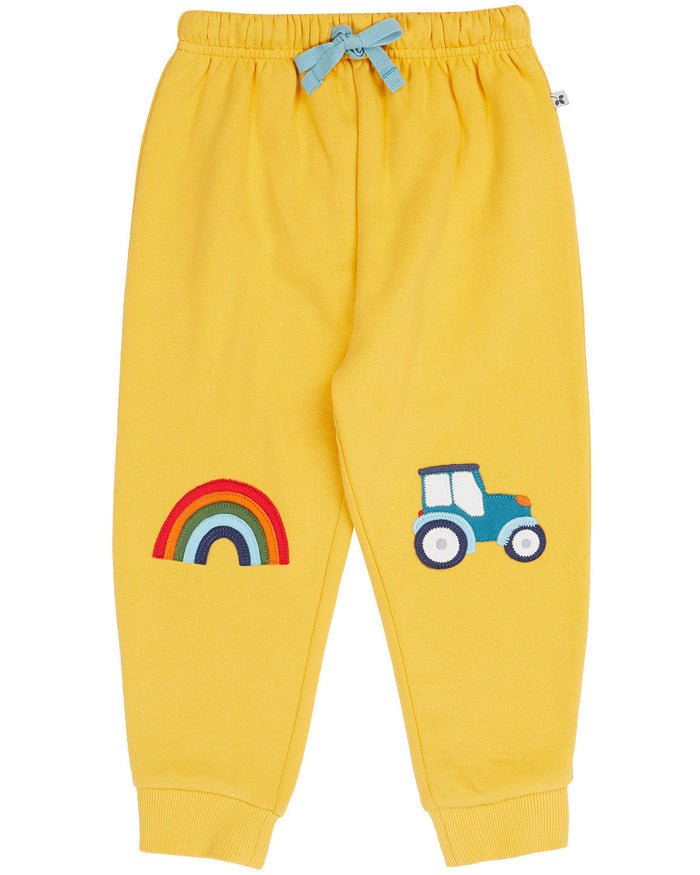Yellow children's pants with rainbow and tractor appliqués on a white background