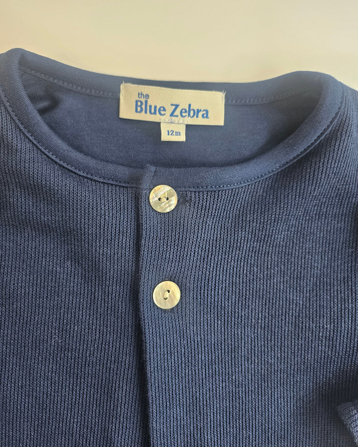 Close-up of a blue garment with 'The Blue Zebra' label on a beige background