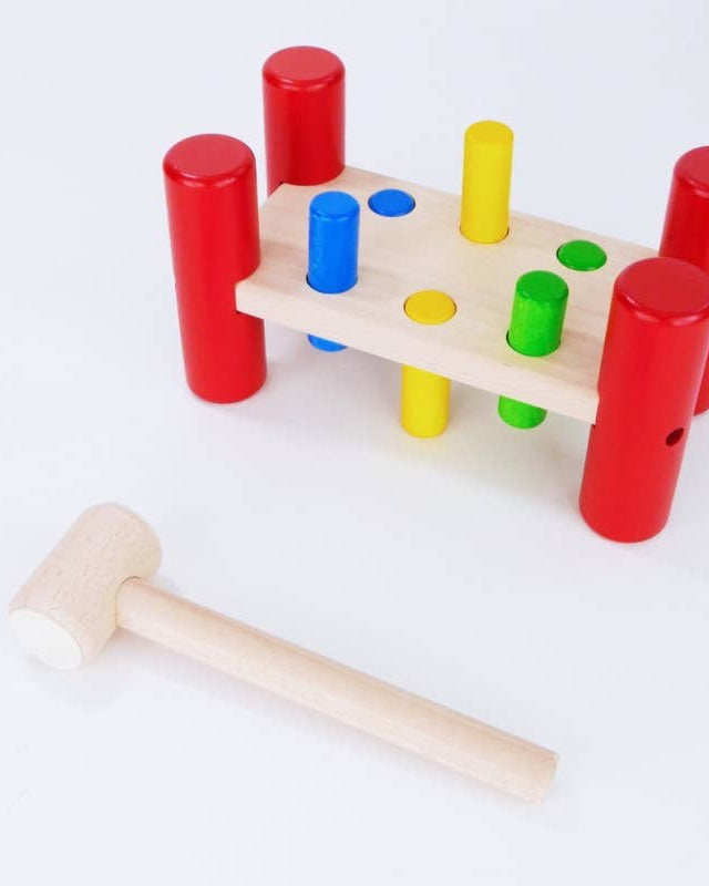 Wooden hammering toy with colorful pegs and a wooden hammer on a white background