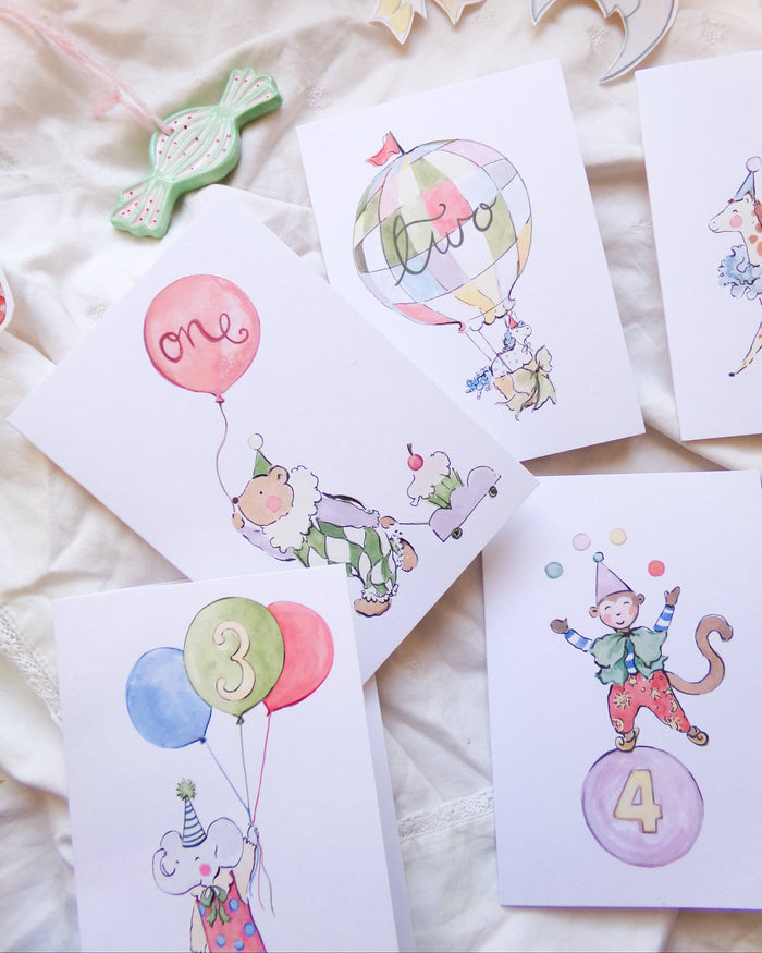 Set of birthday cards with cartoon monkey characters and balloons on a soft surface.