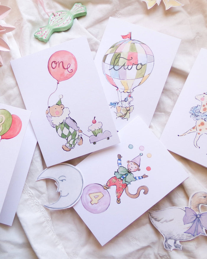 Set of children's cards with illustrations of a clown, balloon, and other decorative elements on a soft fabric background.