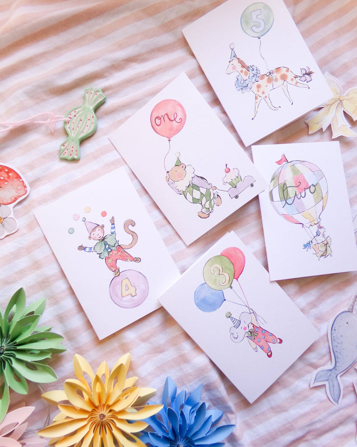 Set of children's birthday cards with colorful balloons and animals on a striped surface.