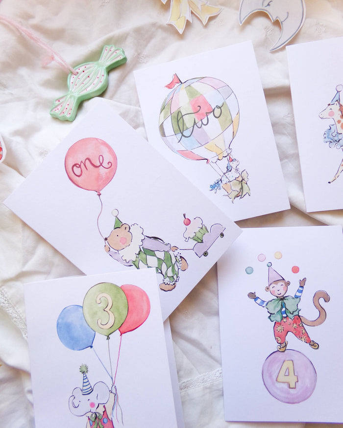 Set of birthday cards with cartoon monkey characters and balloons on a soft surface.