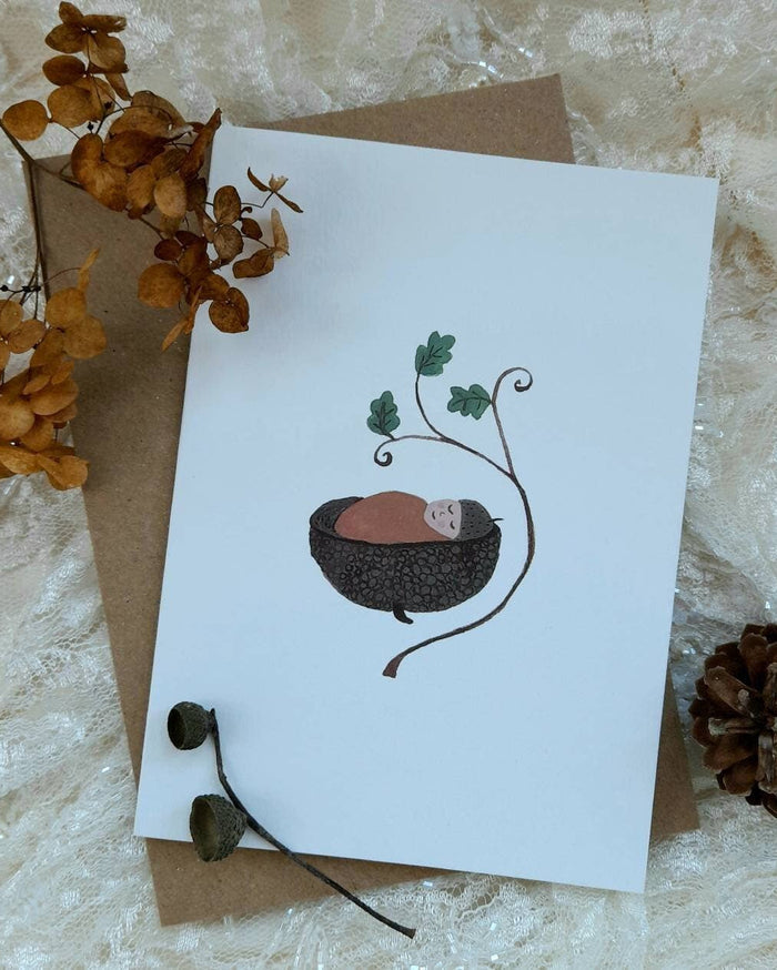Greeting card with a nature-themed illustration on a textured surface with dried flowers and a pine cone.