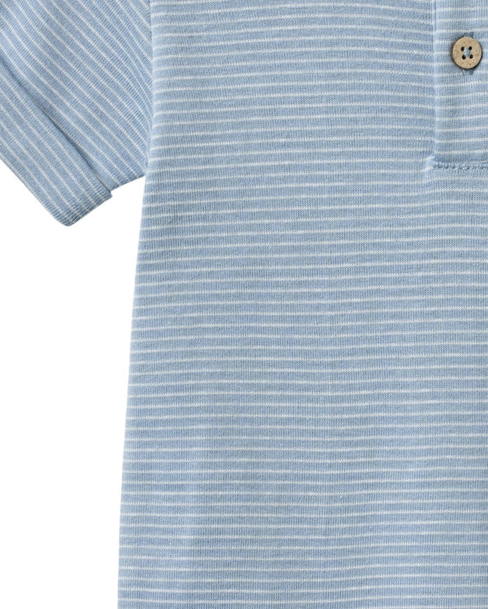 Close-up of a light blue striped polo shirt with a button on a white background