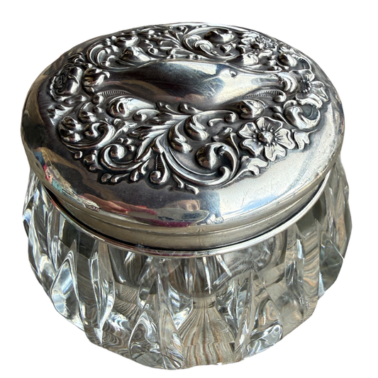 Decorative glass jar with an ornate silver lid on a white background