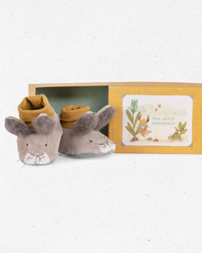 Pair of plush mouse slippers with a decorative card in a box on a white background