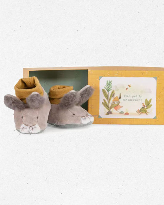 Pair of plush mouse slippers with a decorative card in a box on a white background