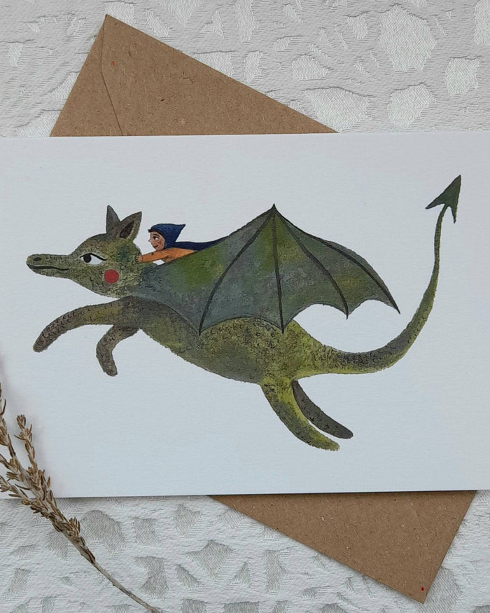 Card with a dragon illustration and a brown envelope on a textured surface.