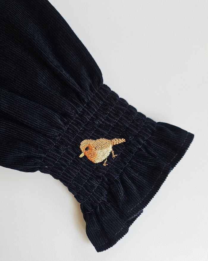 Navy blue fabric with a small embroidered bird design on a white background