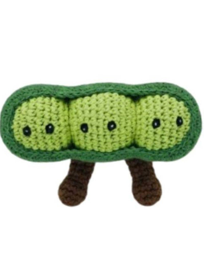Crocheted green pea pod with small black eyes and brown legs on a white background