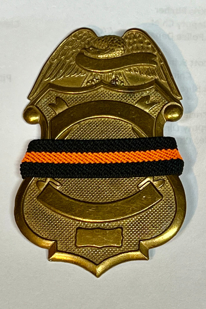 The Stop Gun Violence Wear Orange Awareness / Thin Orange Line Mourning Bands with a thin orange line mourning band 1/2". Band reverses to an all-black mourning band. Public safety officers are wearing thin orange line badge shrouds to raise awareness of gun violence in the community and among police officers, firefighters, Emergency Medical Services and others. Join us in the champagne to Stop Gun Violence. Badges not included.