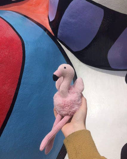Pink flamingo toy held in front of a colorful abstract painting