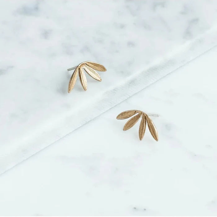 Gold leaf-shaped earrings on a marble surface