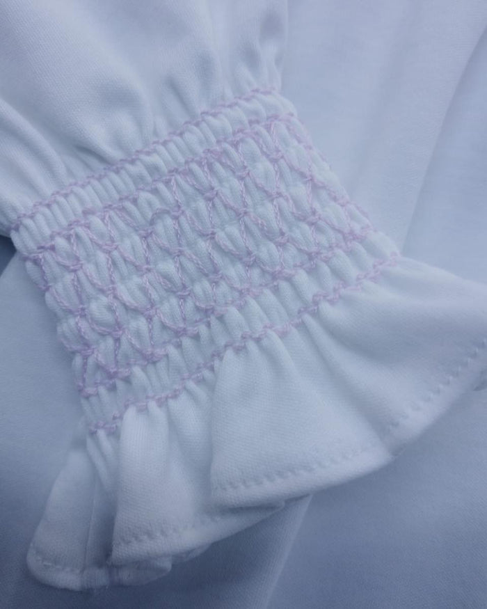 Close-up of white fabric with pink embroidery on a light blue background