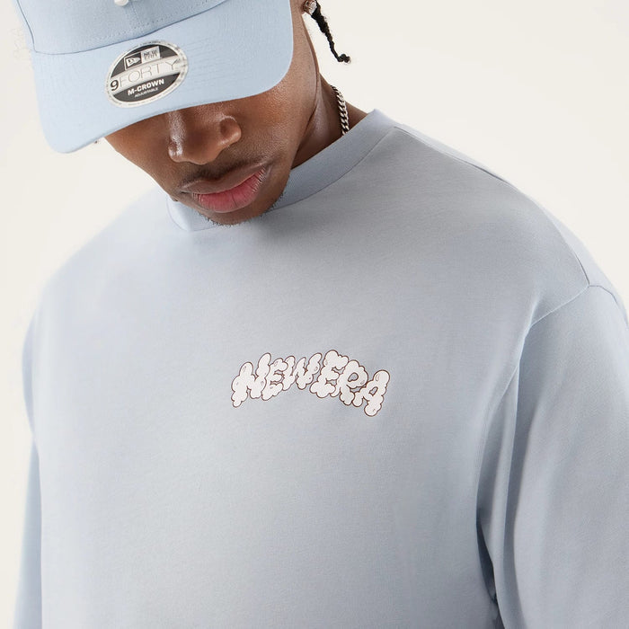 The model is wearing this New Era Fun Block Party Graphic Oversized T-Shirt in pastel blue. 5