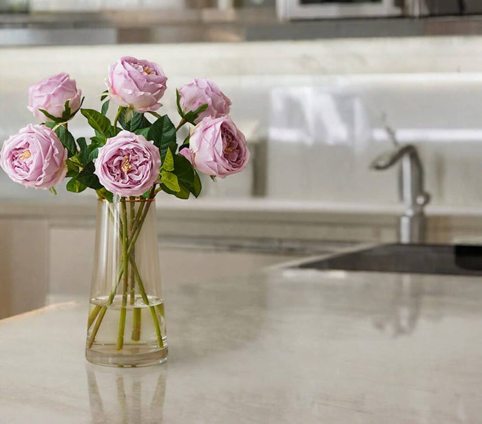 Vase of pink roses on a kitchen counter with a sink in the background