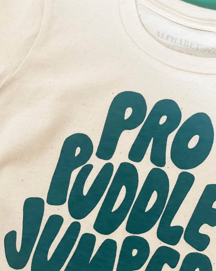 Beige t-shirt with teal text 'PRO PUDDLE JUMPER' on a plain background