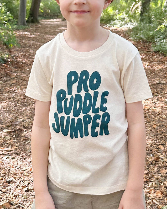 Child wearing a 'Pro Ruddle Jumper' t-shirt in a forest setting