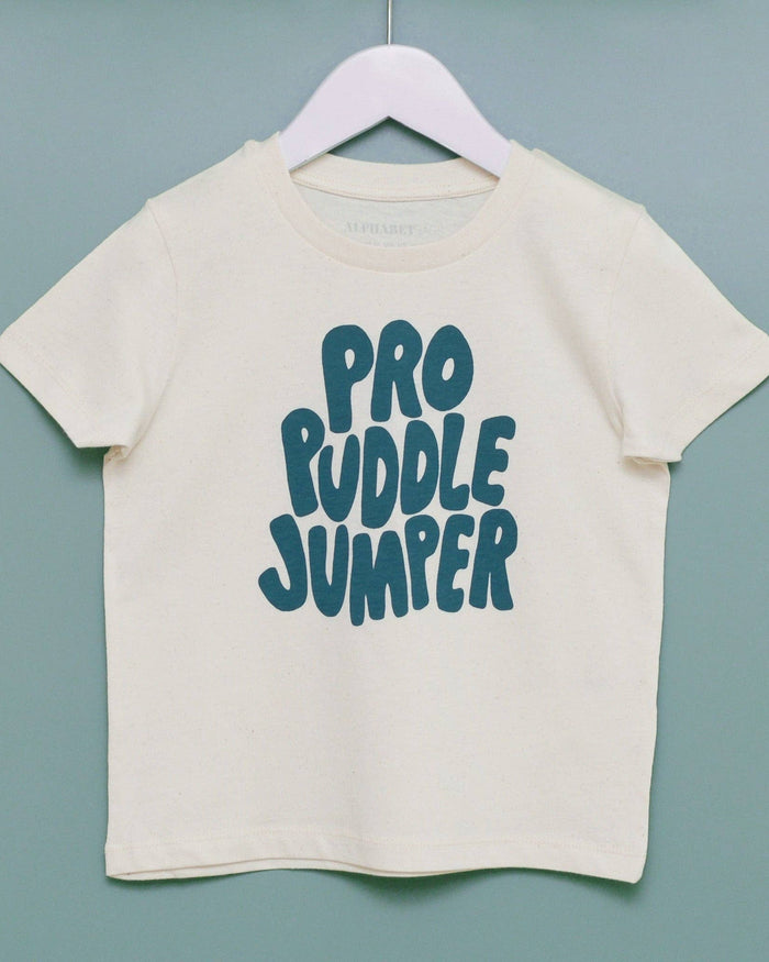 Beige t-shirt with 'Pro Puddle Jumper' text on a hanger against a light blue background