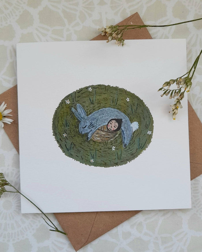 Greeting card with rabbit illustration on a textured surface with flowers