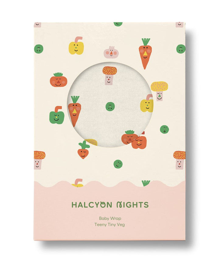 Baby wrap packaging with cartoon vegetables on a beige background, featuring the brand 'Halcyon Nights'.