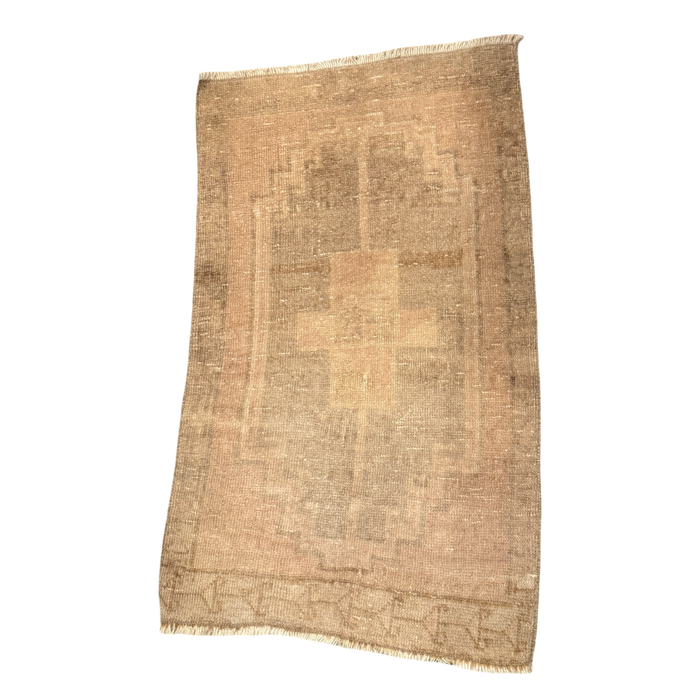 Sand and taupe mini rug with a softly faded geometric design, narrow patterned border, and short cream fringe at both ends.