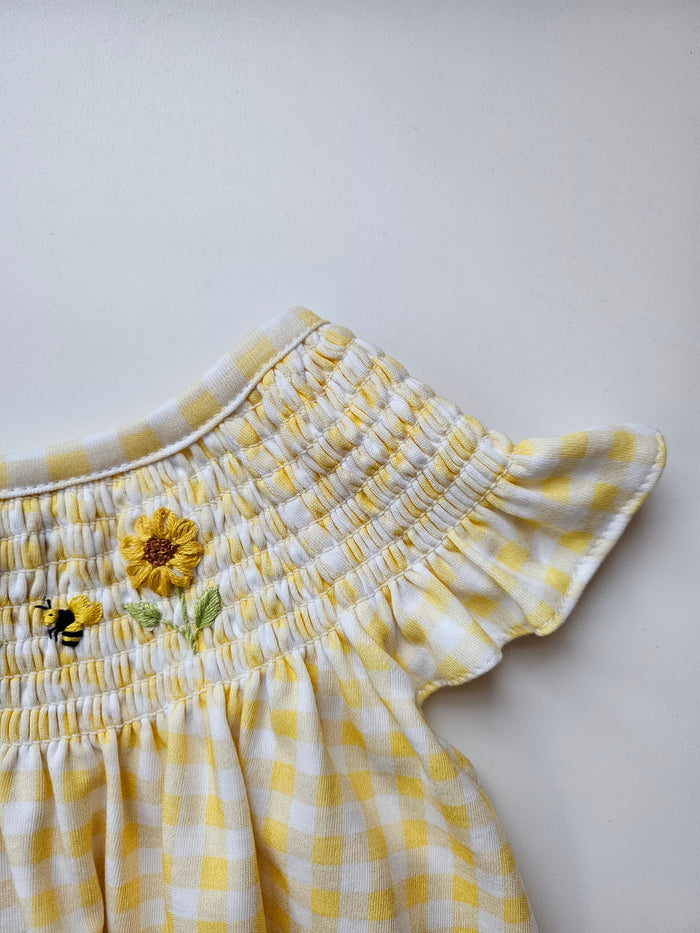 Yellow checkered dress with floral embroidery on a light gray background