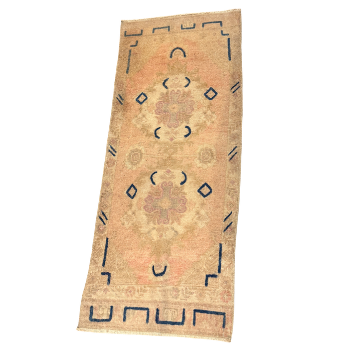 Long peach and beige mini rug with two faded rose medallions, indigo diamonds and curved motifs, angular blue border details, and cream fringe.