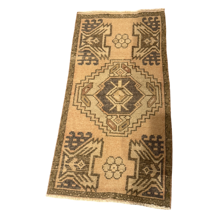 Warm apricot mini rug with a charcoal-centered cream and olive medallion, mirrored geometric corner motifs, small rosettes, and cream fringe.