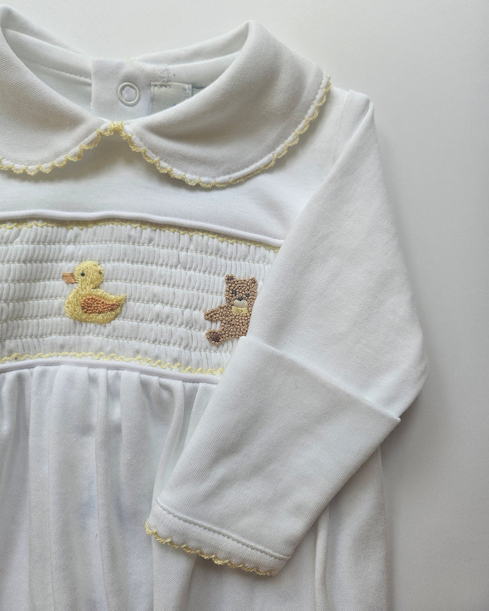 White baby outfit with embroidered bear and duck designs on a light gray background
