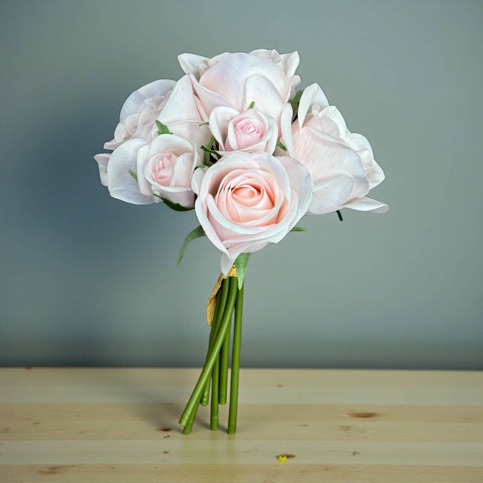 Bouquet of pink and white roses on a wooden surface with a gray background