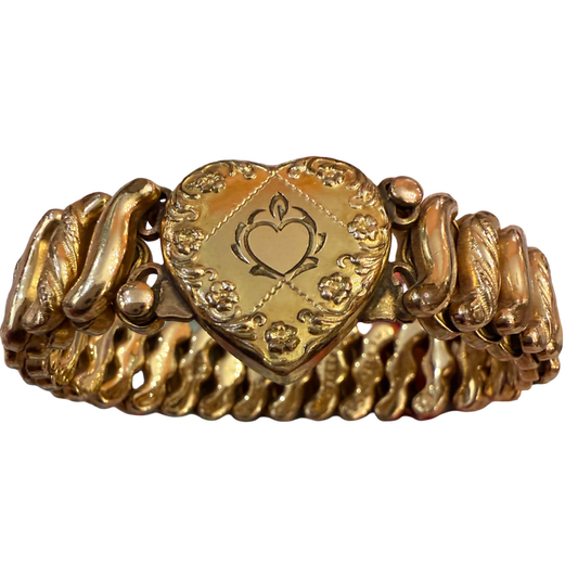 A vintage gold heart-shaped bracelet with a central engraved heart medallion and textured, wavy side bands, shown on a plain white background.