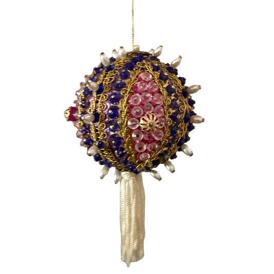 Vintage round ornament with purple beads, pink sequins, gold-tone braid, pearl-look accents, and an ivory tassel hanging from a gold cord.