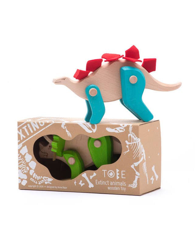 Wooden toy triceratops on top of a cardboard box with other toys inside, on a white background.
