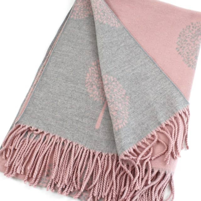 Pink and gray blanket with fringes on a white background